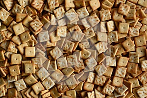 Background texture of small edible squares baked from dough and sprinkled with salt. A lot of salt cracke