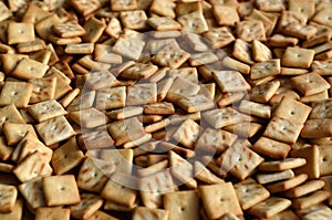 Background texture of small edible squares baked from dough and sprinkled with salt. A lot of salt cracke