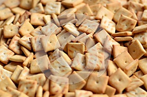 Background texture of small edible squares baked from dough and sprinkled with salt. A lot of salt cracke