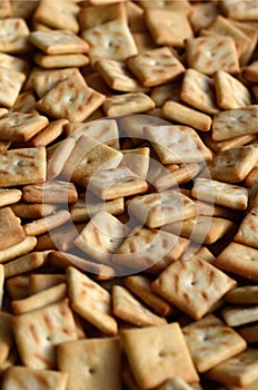 Background texture of small edible squares baked from dough and sprinkled with salt. A lot of salt cracke