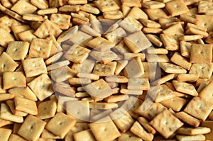 Background texture of small edible squares baked from dough and sprinkled with salt. A lot of salt cracke