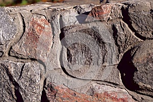 Background texture of a vertical wall of natural stone. Rough rough surface of the stone.