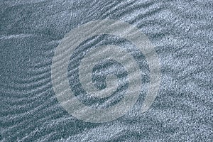 Background, texture, wave pattern of oceanic sand on the beach, blue-gray