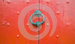 Background texture weathered red wooden door with nail decoration and iron circular door knocker