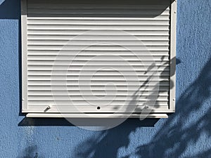 background texture of a white closed plastic window with a rollet on a blue wall background