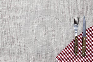 The background to create the restaurant`s menu. Linen tablecloth fork knife on a bright checkered cloth. Is used to create a menu