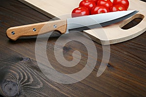 Background of tomatoes and kitchen knife on dark wooden surface