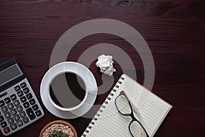 Background top view, flat lay glasses on a blank notebook have a coffee cup, calculator, and cactus on the table desk wooden