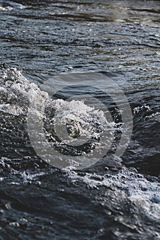 Background, top view, rapid flow river with dark blue water and white foam waves