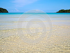 Background of transparent crystal blue sea water surface ripple over sand with sun reflection in summer. Water background. Ocean