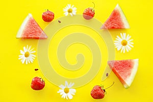Background of triangular slices of watermelon, chamomile and strawberries in a circle on a bright yellow background.