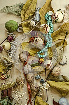 Background with turquoise and coral beads among the yellowed leaves,nuts,dry buds of roses,stones out on light plywood