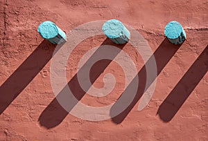 Background - Turquoise corbels and their long shadows on an orange stucco wall on southwestern style building