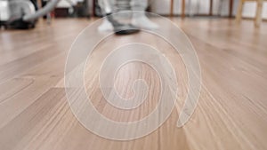 The background in the unfocus guy in white socks vacuums the floor with laminate