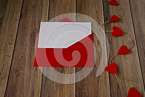 Background for Valentine`s Day. Garland of hearts, red envelope on a wooden background. Valentine