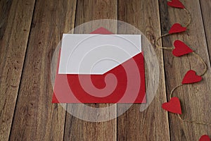 Background for Valentine`s Day. Garland of hearts, red envelope on a wooden background. Valentine