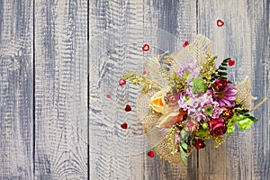 Background Valentine`s Day or wedding. Basket bouquet of roses and chrysanthemums on a vintage wooden background.