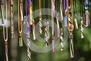 Background of variety of colorful blown glass beads hanging against a green bokeh backdrop - shallow focus