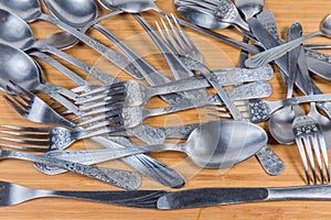 Background of various stainless steel eating utensils on wooden surface