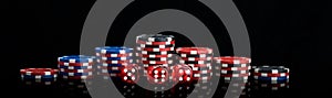Background vertical rows of different poker chips and red dice stand on a black background long photo