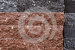 Background, a wall of brown and black facing bricks with a relief texture.