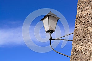 Background with wall-mounted street lamp during daytime on blue sky