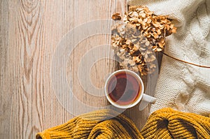 Background with warm sweaters and cup tea. Cozy still life in warm shades, space for text, Autumn winter concept.