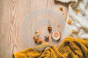 Background with warm sweaters and cup tea. Cozy still life in warm shades, space for text, Autumn winter concept.