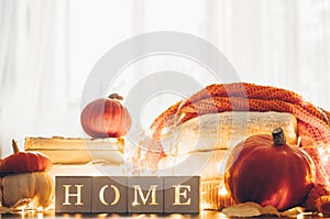 Background with warm sweaters and the inscription HOME. Pile of knitted clothes with leaves, pumpkins. Coziness. Autumn concept