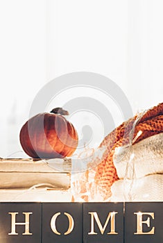 Background with warm sweaters and the inscription HOME. Pile of knitted clothes with leaves, pumpkins. Coziness. Autumn concept