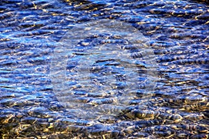 Background of the water of Lake Traunsee in the coastal area. Colorful texture of stones under water