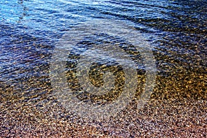 Background of the water of Lake Traunsee in the coastal area. Colorful texture of stones under water