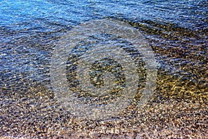 Background of the water of Lake Traunsee in the coastal area. Colorful texture of stones under water