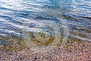 Background of the water of Lake Traunsee in the coastal area. Colorful texture of stones under water