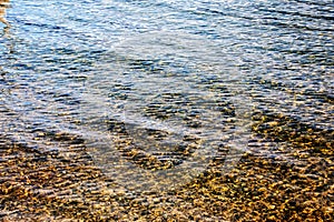 Background of the water of Lake Traunsee in the coastal area. Colorful texture of stones under water
