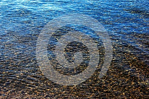 Background of the water of Lake Traunsee in the coastal area. Colorful texture of stones under water