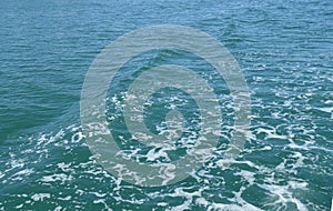 Background with wave and foam, trace on the surface of the water behind the fast moving ship