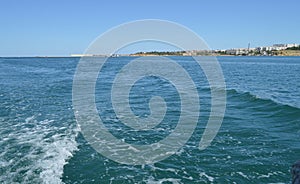 Background with wave and foam, trace on the surface of the water behind the fast moving ship