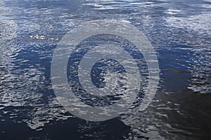 Background - wavy water surface with reflection of sky and clouds