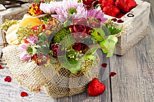 Background wedding or Valentine`s Day. Basket bouquet of roses and chrysanthemums on a vintage wooden background.