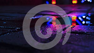 Background of wet asphalt with neon light. Blurred background, night lights of a big city, reflection, puddles.