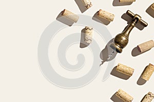 Background with wine corks and old bottle opener for white and red wine on beige pastel color with shadow at sunlight