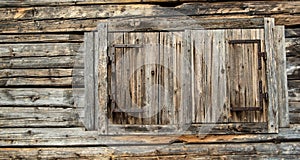 wall of an old wooden house with windows closed by shutters