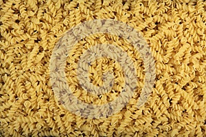 Background of yellow Italian pasta rolled up in a spiral. View from above.