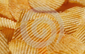 Background with yellow potato chips riffle. Close-up view. Natural product