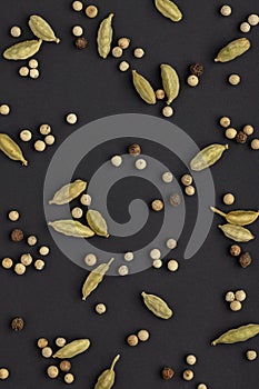 Backgrounds and textures, spices. Cardamom and peppercorns on a black background.