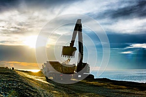 Backhoe or digger working with bucket at industrial earth excavation site