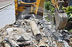 Backhoe digging Asbestos cement pipe.