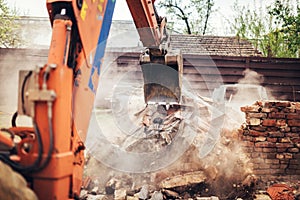 Backhoe excavator scoop demolishing ruins, destroying and loading debris