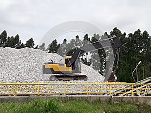 Backhoe and Large piles of limestone for use in lime kiln line with blue sky and cloud